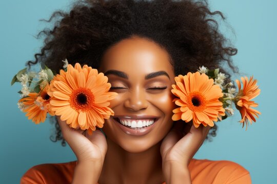 beautiful african american woman with bright flowers near her face, smelling the scent of flowers smiling, bright turquoise background