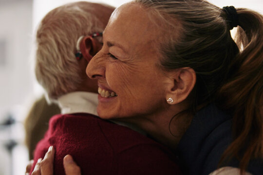 Smiling senior friends greeting together with a hug