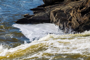 Spring landscape with a stormy northern river with stone banks and ice on the rocks