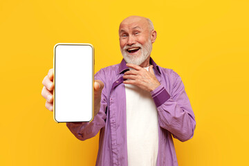 old bald grandfather in purple shirt shows blank smartphone screen on yellow isolated background
