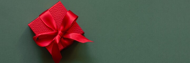 Red (scarlet) box (gift) on a green background. Festive concept, present for birthday, Christmas,...