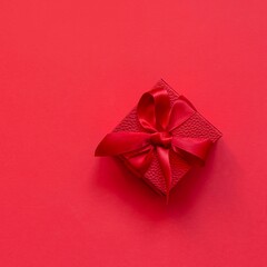 Red (scarlet) box (gift) on a red background. Festive concept, present for birthday, Christmas, Valentine's day, mothers Day.