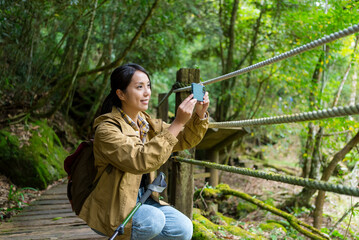 Fototapeta premium Woman use cellphone to take photo in forest hiking