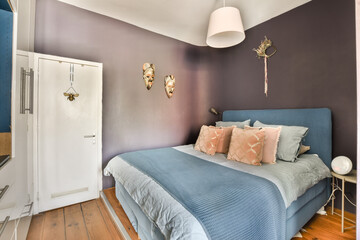Fototapeta na wymiar a bed in a room with purple walls and white trim around the headboard, blue bedspremn