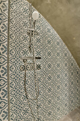 a tiled bathroom with a shower head and hand held to the wall, as if it is not in use