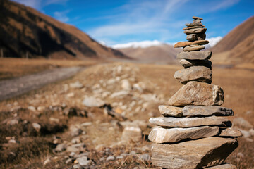A carefully stacked cairn of flat stones stands in sharp focus against the soft backdrop of a...