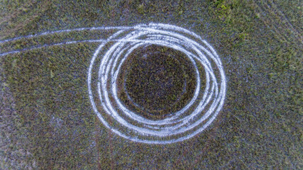 Fototapeta na wymiar Spiral pattern tracks on sand carved into green landscape.