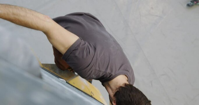 Fit young man jumping down to the floor from a climbing wall with friends watching during a day together at a bouldering gym