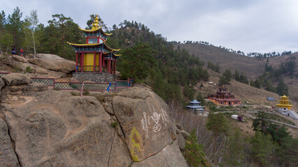 Colorful Mongolian temple perched on rocky cliff.