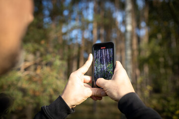 Mann fotografiert im Wald mit dem Handy, Empfang, Netzabdeckung, Live view