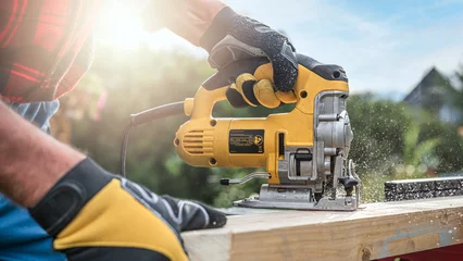 Tuinposter Electric curve saw in worker hand during wavy cutting the wooden batten. © Sabrewolf