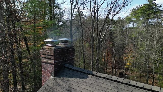smoke coming from chimey of a suburban home in the woods (rural house drone footage shot from above) shingles, roofing, fireplace exhaust, country home, rustic luxury architecture