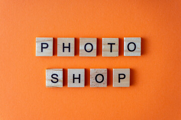 Word photo shop. The phrase is laid out in wooden letters top view. Orange flat lay background.