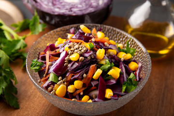  Fresh salad with red cabbage, carrots, hemp seeds and corn in a bowl on the table