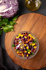  Fresh salad with red cabbage, carrots, hemp seeds and corn in a bowl on the table, vertical photo top view