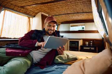 Happy man using digital tablet inside of his camper van.