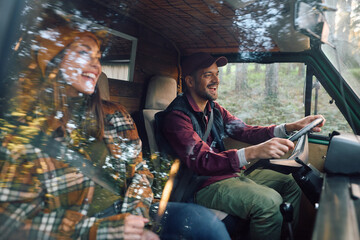 Cheerful couple of campers traveling through nature in van.