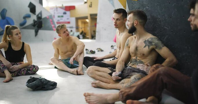 Group of fit young friends in sportswear talking together during a break from a rock climbing session in a bouldering gym
