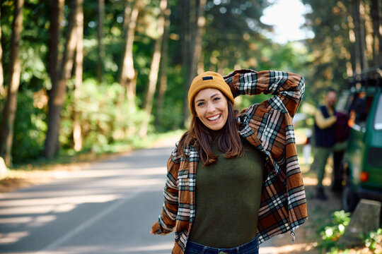 Happy woman stretching after traveling in camper van in nature.