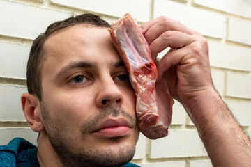 A man applies raw meat to a bruise on his face