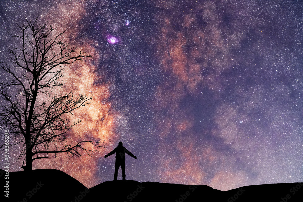 Wall mural silhouette of a hiker standing on the hill, on the milky way galaxy background. cosmos wallpaper.