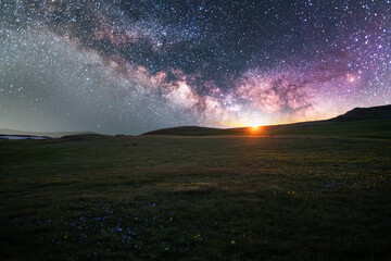 Beautiful night landscape, bright milky way galaxy over green field.
