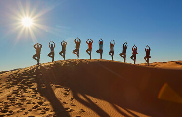 A group of tourists captures joyful moments, striking playful poses, silhouetted against the...