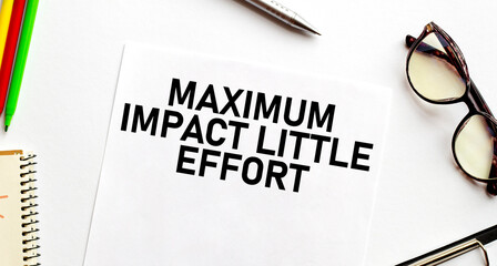 MAXIMUM IMPACT LITTLE EFFORT words on paper with pen glasses and pencils