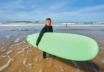 A young surfer strikes a pose with his board on the oceanfront in Essaouira
