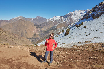 Fototapeta premium A tourist on the Atlas Mountains pass, with snow-capped peaks behind