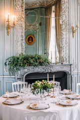 Wedding. Banquet. There are tables with white tablecloths in the bright hall. On the tables are compositions of flowers and greenery, plates, glasses, cutlery and napkins