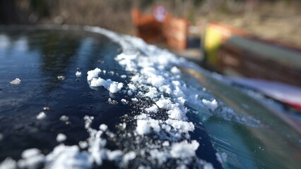 Morning frost on top of car vehicle after scraping ice from windshield glass