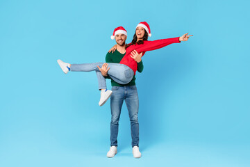 Joyful couple in Santa hats having fun posing in studio
