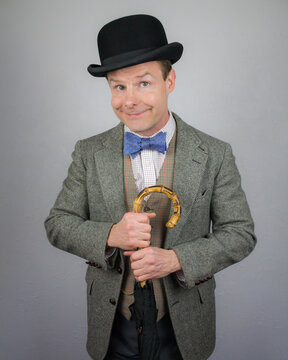 British Character in Tweed Suit and Bowler Hat Holding Umbrella and Smiling. Concept of Vintage Vaudeville Comic Actor