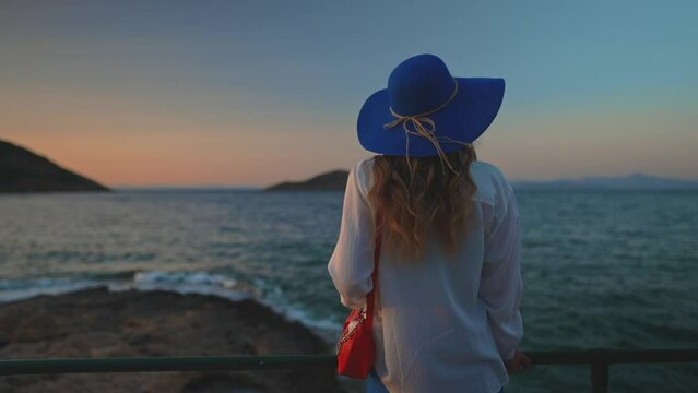 Tourist female in a blue hat by the sea.