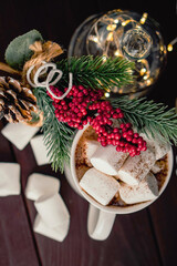 Christmas drink hot chocolate with marshmallows at festive illuminated decoration. Selective focus