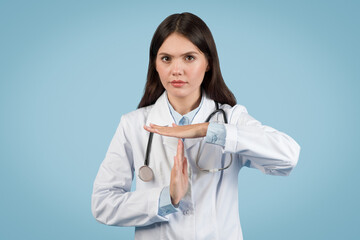 Serious female doctor showing time out hand gesture