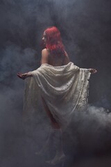 Alluring mysterious woman with veil in smoky room