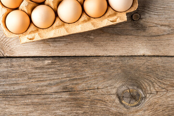Chicken eggs in box on wooden table with copyspace. Top view