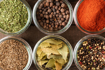 Collection of spices in bowls on wooden background. Top view