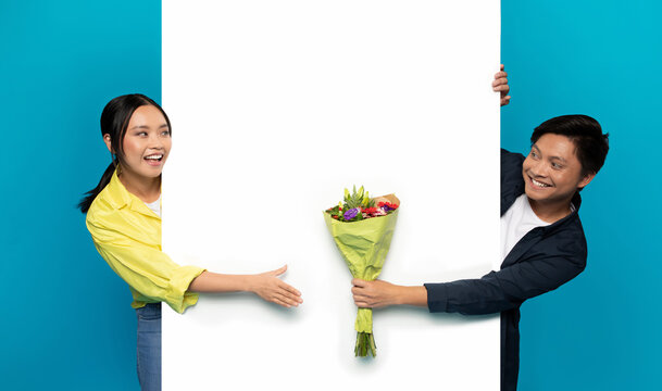 Smiling millennial asian man in casual give bouquet of flowers to woman on big banner