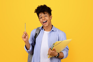 Cheerful black male student with pen and folders