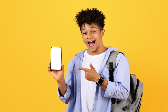 Excited black man student showing and pointing at phone with blank screen