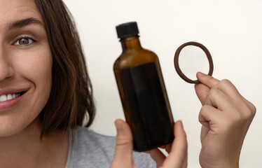 Fototapeta premium happy millennial woman showing healthy hair,holding elastic and oil treatment,many plastic blisters.girl brushing with eco wooden comb,doctor hand in surgical glove.brown dark bottle with serum