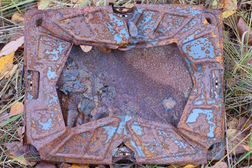 one brown rusty bent iron box lies on the grass on the street