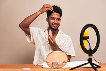 Latin man applying skin product at home with mirror and light