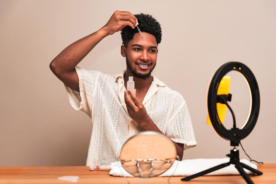 Latin man applying skin product at home with mirror and light