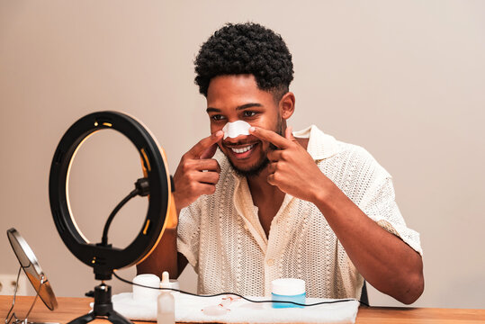latin man applying skincare routine with smile