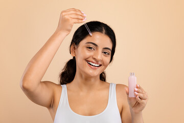 Skincare Cosmetics. Beautiful Indian Lady Holding Open Bottle With Moisturizing Face Serum