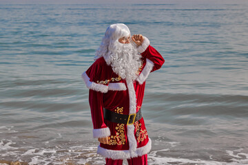 Santa Claus at sea on a hot summer day. Standing ankle-deep in water with his pants rolled up. Xmas...